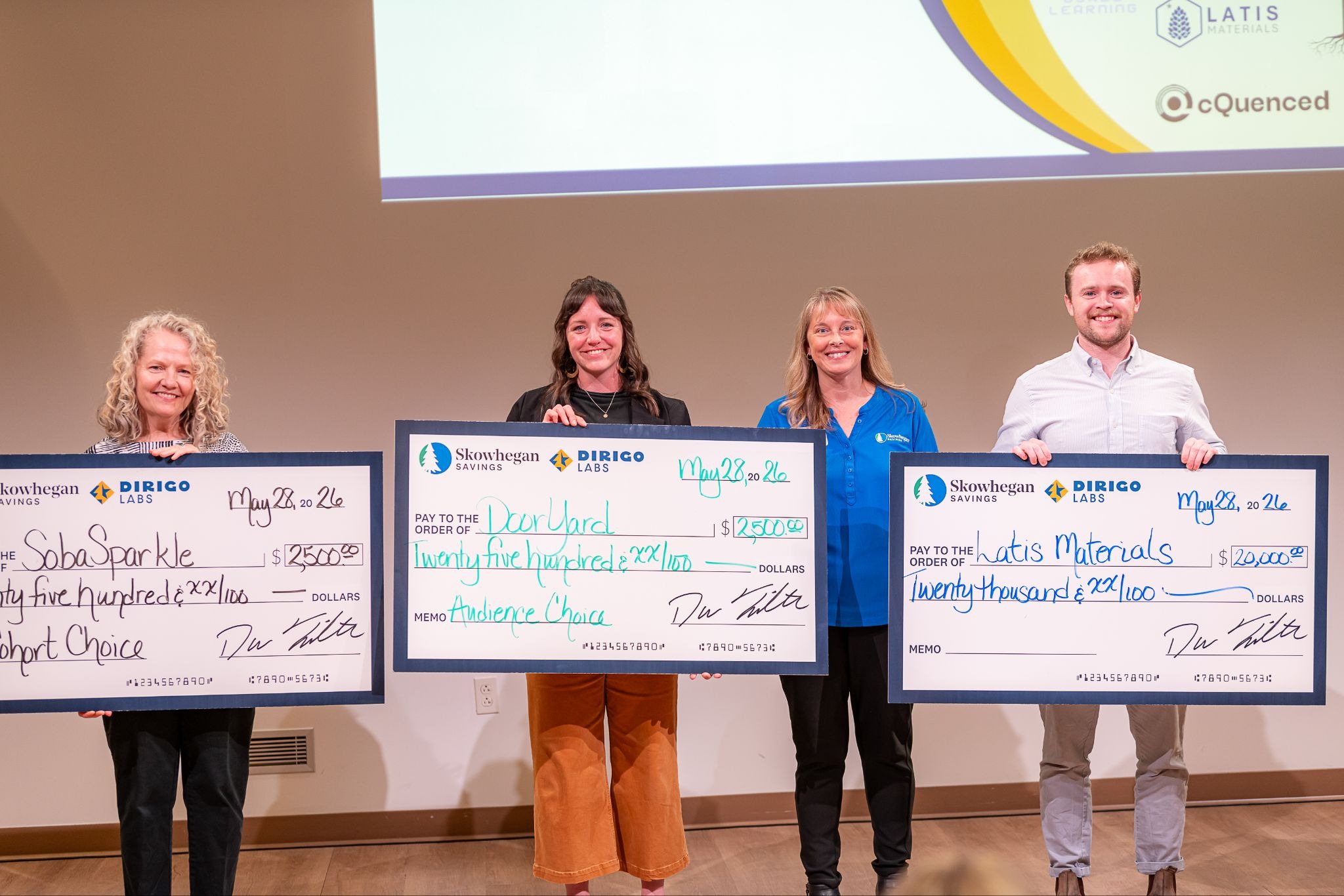 The 2026 Dirigo Labs Pitch Competition winners holding their prize checks on stage at Greene Block + Studios in Waterville